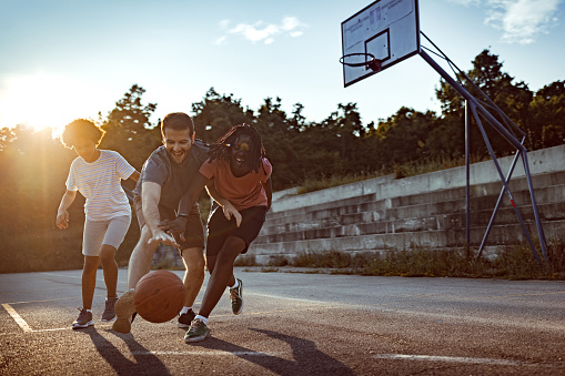Photo of family playing basketball on sport court.