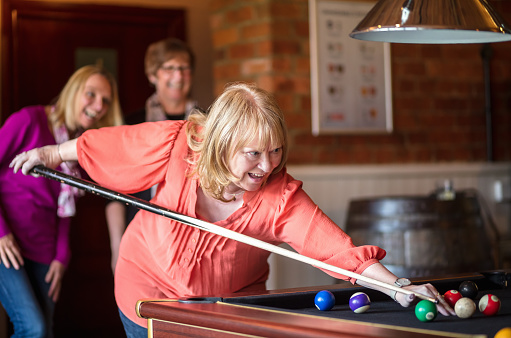 A group of three middle aged women playing pool.